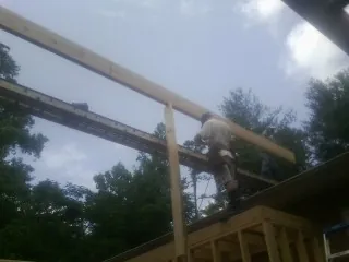Carpenter setting a ridge beam over a new addition frame — Ice Dam Removal by Roofing Brothers in Eighty Eight
