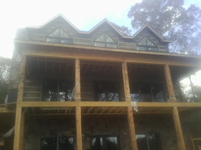 Dormers and porch framing on a large log home under construction — Roof Coating work by our crew in Eighty Eight