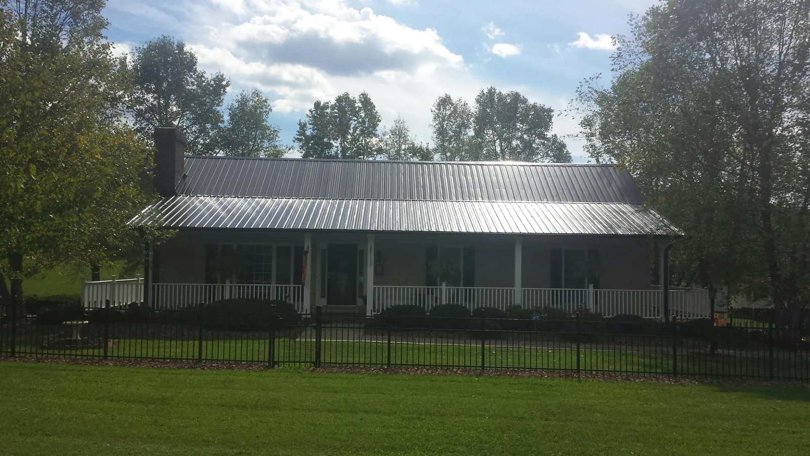 Gray metal roof on a brick ranch with a full width front porch — Gutter Guard Installation work by our crew in Eighty Eight