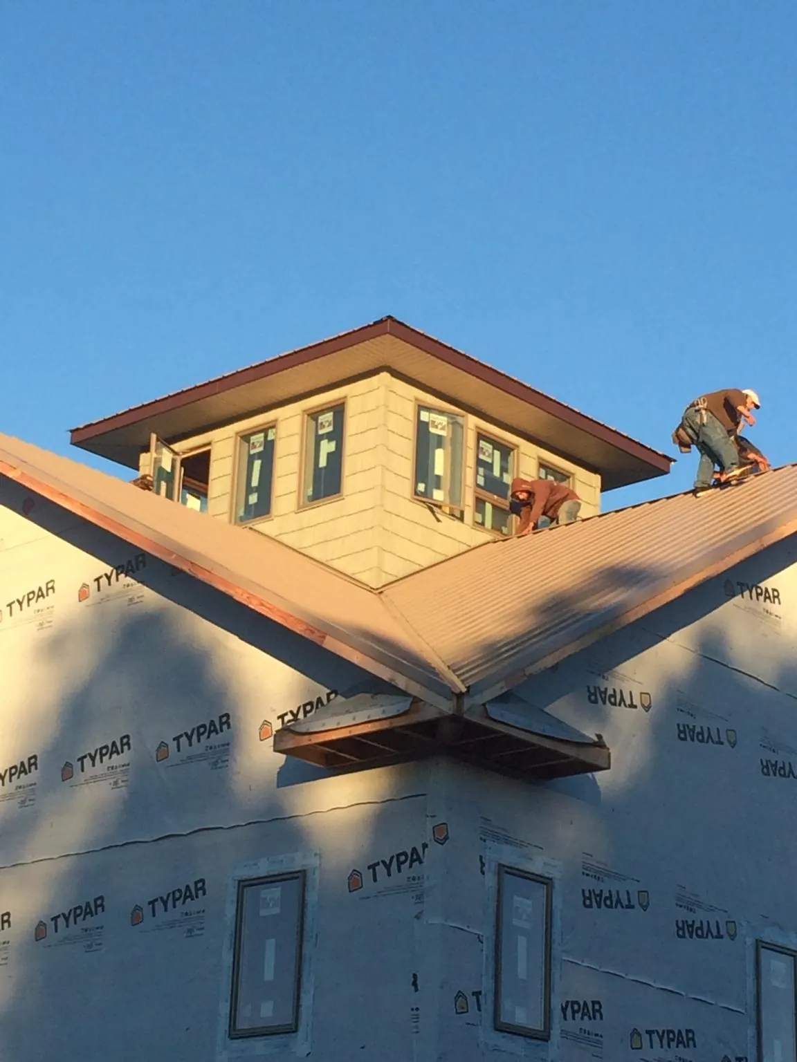 Roofers working around a rooftop cupola on a new metal roof at sunset — Roof Waterproofing in Eighty Eight by Roofing Brothers